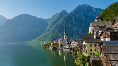 Yükselen dağların arasında, Hallstatt 'ın pitoresk köyü göl kenarını süslüyor, sabahın erken saatlerinde banyo yapıyor. Eski evler kıyı şeridini dolduruyor, çarpıcı bir göl manzarası yaratıyor..