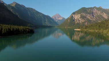 Plansee Avusturya Gölü, sabah güneşinin altında görkemli dağlarla çevrili. Yüksek kalite 4k görüntü