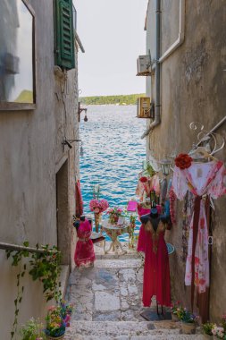 Rovinj Hırvatistan 27 Ağustos 2024 'te, Rovinj' in kalbinde, dar bir sokakta asılı duran renkli giysiler, çiçeklerle süslenmiş resimli bir rıhtım tablosuna yol açtı.