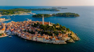 Hırvatistan 'ın Rovinj kıyı kentinde, tarihi mimarisi ve canlı limanının altını çizen altın güneş ışığı görülüyor. Gündüzün huzurlu bir akşama dönüşmesi gibi kayıklar yavaşça suda sallanıyor..