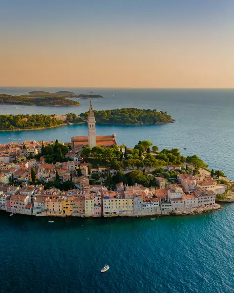 Kıyı şeridine yapışmış renkli evler gibi gün batımının sıcacık parıltısı Rovinj 'i sarıyor. Çan kulesi heybetli bir şekilde yükseliyor, sakin sular ve uzak adalarla çevrili, güzel bir manzara yaratıyor..