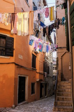 Rovinj 'in pitoresk sokaklarında, rüzgarda sallanan canlı giysiler, tarihi binaların sıcak renklerine renk katar, deniz kenarındaki yaşamın canlı ruhunu somutlaştırır..