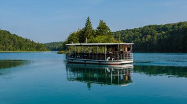 Hırvatistan 'daki Plitvice Gölleri 1 Eylül 2024' te, Plitvice Gölleri 'nin kristal berrak sularında bir ahşap tekne süzülüyor. Yeşilliklerle çevrili