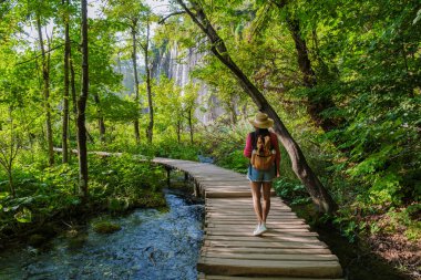 Ahşap patikalar boyunca gezinirken Plitvice Gölleri 'nde canlı yeşillikler ve kristal berrak sularla çevrili bir huzur bulunur. Doğanın güzelliği keşif ve yansımayı davet eder..