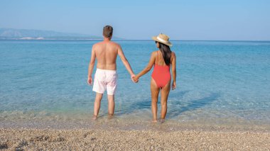 Brac Adası 'nın berrak sularının kenarında el ele duran bir çift güneşin altında sakin bir günün tadını çıkarıyor. Islak kumlu sahil ve yumuşak dalgalar romantizm için mükemmel bir zemin oluşturur..