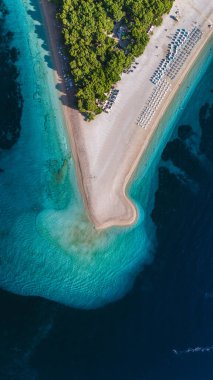 Kristal berrak turkuvaz suları Hırvatistan 'ın Brac Adası' nın altın kumlu sahilini kucaklayarak, ziyaretçileri yemyeşil yemyeşil yemyeşil çevrelerle çevrili sıcak güneşin altında rahatlatıcı bir güne davet ediyor..