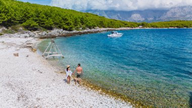 Brac Adası 'nın çakıl taşlı kıyı şeridi boyunca birkaç yürüyüş, güneşi emerek.