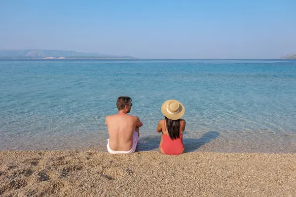 stock image Visitors unwind on the sandy shore of Brac Island, enjoying the calm waters and beautiful scenery. The warm sun casts a golden glow, Zlatni Rat Beach