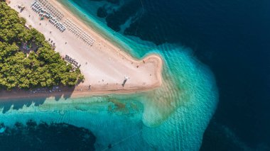 Altın kumlu kıyılar, ziyaretçilerin güneşlenmenin ve mükemmel yaz havasında yüzmenin keyfini sürdükleri Brac Adası 'nda canlı turkuaz sularıyla karşılaşıyor Zlatni Rat Sahili Hırvatistan