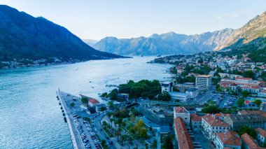 Güneş Kotor 'un üzerinde batarken, canlı renkler körfezin sakin sularını yansıtıyor, görkemli dağların arasına yerleşmiş görkemli kıyı kasabasını vurguluyor..