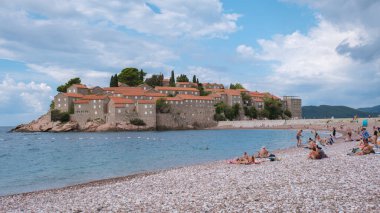 Sveti Stefan Montenegro 12 Eylül 2024 'te, ziyaretçiler Sveti Stefan, Karadağ yakınlarındaki sakin plajın keyfini çıkarırken, dalgalar yavaşça kıyıya vururken güneşin tadını çıkarıyorlar.