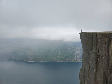 Cesur bir kaşif Norveç 'teki sislerle kaplı bir fiyordun dramatik uçurumlarına ve dingin sularına bakıyor. Önceki Norveç
