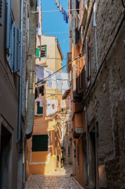 Rovinjs 'in resimli dar sokaklarında dolaşın, renkli binalar ve asılmış çamaşırların canlı bir atmosfer yarattığı yerlerde. Altın güneş ışığı kaldırım taşlarının üzerine sıcak bir parıltı saçar..
