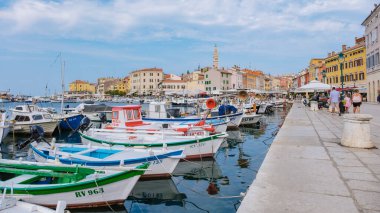 Rovinj Hırvatistan 27 Ağustos 2024, Rovinj 'in sakin sularına renkli tekneler demirledi. Tarihi binaların canlı cepheleri bu güzel sahil kasabasının cazibesini yansıtıyor.