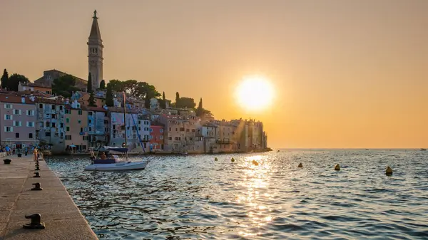Güneş Rovinj 'in üzerinde batarken, altın renkler büyüleyici sahil kasabasını yıkıyor. Yelkenliler limanın yakınında yavaşça sallanırken, canlı binalar sıcak ışığı yansıtarak, sakin bir atmosfer yaratıyor..