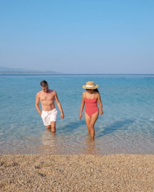 İki birey, Brac Adası 'nın pitoresk sahili boyunca, berrak ve sığ sularda el ele yürür. Üzerlerinde sıcak güneşin parladığı sakin bir yaz gününün tadını çıkarırlar..