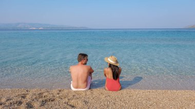 Hırvatistan 'ın Brac Adası' nın sakin sularında sıcak güneşin tadını çıkaran bir çift görülüyor. Sahil manzarası ve yumuşak dalgalar rahatlamak için mükemmel bir kaçış yaratıyor..