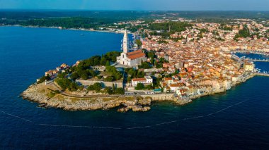 Günbatımının ılık renkleri Rovinj 'in tarihi binalarını aydınlatıyor, sakin suları yansıtıyor.