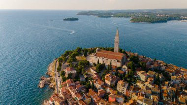 Büyüleyici sahil kenti Rovinj 'e bakan manzara, renkli binalar, tarihi mimari ve huzurlu denizi ön plana çıkarıyor ve sıcak akşam ışığında yıkanan huzurlu bir manzara yaratıyor..