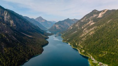 Kristal berrak sular Plansee 'yi çevreleyen yüksek tepeleri nazikçe yansıtıyor. Yürüyüşçüleri ve doğa severleri bu dağ cennetinin huzurlu güzelliğini keşfetmeye davet ediyor..