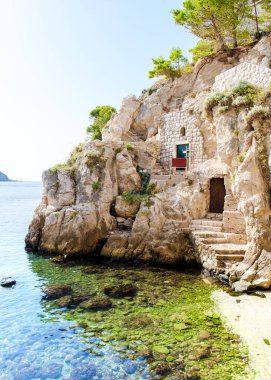 Dubrovnik 'teki berrak mavi suların kıyısındaki engebeli bir uçuruma kurulmuş büyüleyici bir taş yapı. Denizde güneş ışığı parıldıyor, bu güzel kıyı manzarasını keşfetmeye davet ediyor..