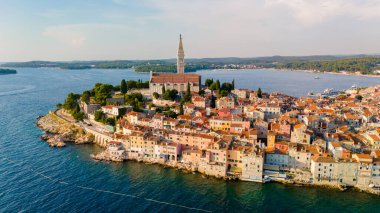 Rovinj 'in dingin sularına uzanan dolambaçlı sokaklar. Renkli şehrin üzerinde altın güneş ışığı altında yükselen çan kulesi, keşif ve maceraya davetiye çıkarıyor..