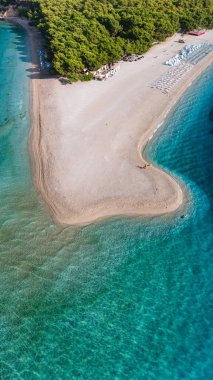 Brac Adası 'nın sakin kumlarının tadını çıkarın. Nazik dalgalar kıyıya vururken. Yeşillik, Hırvatistan 'da doğal ihtişam için mükemmel bir gün olan bu güzel plajı süslüyor. Zlatni Rat Sahili Hırvatistan