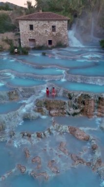 Tuscany, İtalya 'da Satürn' de bulunan güzel termal banyoları ve çarpıcı şelaleleri deneyin. Toskana 'daki termal şelalede bir çift kadın ve erkek.