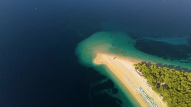 Hırvatistan 'ın Brac Adası' ndaki baş döndürücü Zlatni Rat Sahili 'ni ziyaret edin. Turkuaz suların yumuşak altın kumlarla buluştuğu ve doğal güzelliklerin keyfini çıkardığı yer. Bu gizli mücevheri özlemeyin.