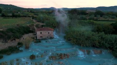 Akşam havasında buhar yavaşça yükselirken turkuaz termal yayların dingin güzelliğini keşfedin. Terim di Saturnia, Satürn 'deki jeotermal sülfür pınarları, İtalya Toscane Kaplıcaları