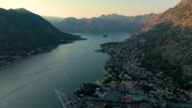 Güneş batarken, Kotor Körfezi Karadağ çarpıcı dağlar ve tuhaf kıyı evleriyle çevrili sakin sulara yansıyan ılık renklerle dönüşüyor. Doğadaki huzurlu an güzel bir şekilde gözler önüne seriliyor..