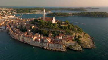 Güneş batarken Rovinj Hırvatistan 'ın nefes kesici kıyı şeridini görün, büyüleyici binalar ve sakin sular üzerine sıcak bir parıltı saçın..