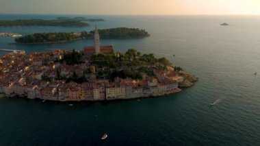 Adriyatik Denizi Hırvatistan 'ında güneş batarken Rovinj' in büyüleyici güzelliğini deneyimlemek, tarihi binaları aydınlatmak ve barışçıl bir atmosfer yaratmak.