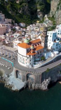 Büyüleyici bir manzara, dingin mavi sularla tamamlanmış kayalıklara tünemiş Amalfi Atraniseched 'in büyüleyici mimarisini yakalıyor. Şafak ışığı binaları yıkıyor, sakin bir atmosfer yaratıyor..