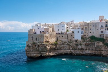 Polignano a Mare Vibrant beyaz binalar engebeli uçurumlara tutunur, sakin turkuaz sulara bakar. Ziyaretçiler açık ve güneşli bir günde İtalya 'nın güzel Puglia kentindeki çarpıcı kıyı manzarasının tadını çıkarıyorlar..