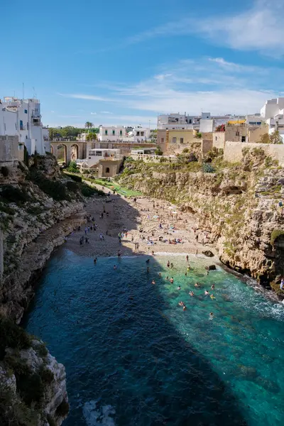 Polignano ve Karabasan Ziyaretçiler sıcak güneşin tadını çıkarırken Puglia 'nın sakin ve çarpıcı sahil şeridinin tadını çıkarırken, İtalya' da kayalıklar sakin mavi bir körfezi çerçeveliyor.