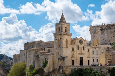 Matera, Puglia, İtalya 'nın tarihi sokaklarında gezen ziyaretçiler, güzel bir günde tüylü bulutların çerçevelediği eşsiz taş binalara ve nefes kesici manzaralara hayran kaldılar..