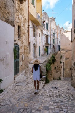 Matera 'nın antik kaldırım taşı sokaklarında gezinen bir ziyaretçi, bu tarihi kasabanın güzel mimarisinin ve dingin atmosferinin tadını çıkarıyor. Puglia İtalya