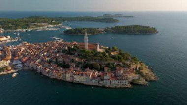 Hırvatistan 'ın pitoresk bir adasında yuva yapmış büyüleyici sahil kasabası Rovinj' i keşfedin, güneş batarken, tarihi binaların üzerine altın renkler dökerek ve parıldayan deniz.
