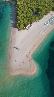 Zengin yeşilliklerle çevrili sakin bir plajın güzelliğini keşfedin, ziyaretçiler güneşlenmeyi ve su aktivitelerini severler. Turkuvaz suları ve yumuşak kumlar, Brac Adası Hırvatistan