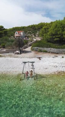 Sahilde neşeyle sallanan bir çift kristal berrak suyun yanında güneşin tadını çıkarıyorlar. Huzurlu sahil manzarası ve bereketli yeşillik, Brac Adası Hırvatistan 'da huzurlu bir atmosfer yarattı.
