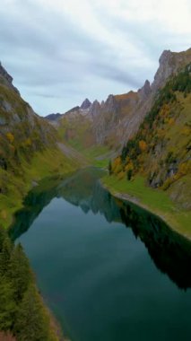 Falensee Gölü 'nün sakin sularını, görkemli Alpler tarafından çevrelenmiş, sonbahar renklerini ve huzurlu yansımalarını görün. Doğa sanatı bu resmedilmiş İsviçre manzarasında sergileniyor. İsviçre