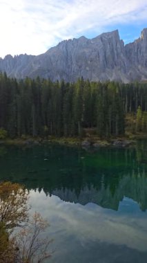 Huzurlu bir göl, etrafını saran yüksek dağları ve yemyeşil ormanları yansıtır. Sonbahar renkleri su yüzeyinde dans eder, Dolomitlerde Karersee gölü, Güney Tyrol, İtalya, Carezza gölü olarak da bilinir.