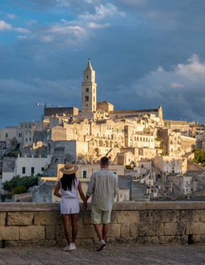 Matera İtalya 'da güneş batarken, bir çift el ele tutuşurken çarpıcı antik taş yapılara hayran kalıyor. Yumuşak parıltı tarihi şehri aydınlatıyor, büyüleyici bir romantizm atmosferi yaratıyor..