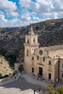 Ziyaretçiler Matera 'nın tarihi sokaklarında geziniyor. İnanılmaz kayalık tepelerle çevrili, canlı bir gökyüzü altında. Güney İtalya' daki bu kültürel mücevherin özünü yakalıyorlar..