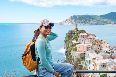 Güneşli bir uçuruma kurulmuş bir gezgin Cinque Terre 'nin renkli evlerini izlerken neşeyle ışıldıyor. Işıl ışıl Akdeniz uzanır aşağı, Vernazza İtalya