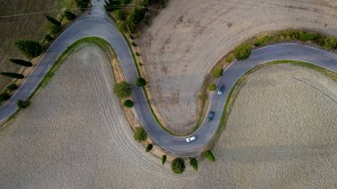 Altın tarlaların arasında zarifçe kıvrılan dolambaçlı bir yol batan güneşin yumuşak parıltısı altında keşfi davet ediyor, Tuscany 'nin sakin manzarasının güzelliğini gözler önüne seriyor..
