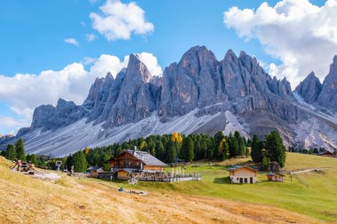 A breathtaking view unfolds in the Dolomites of Italy, showcasing rustic mountain cabins nestled against towering peaks. Geisleralm Dolomites Val Di Funes in Italy Puez Odle Nature Park clipart