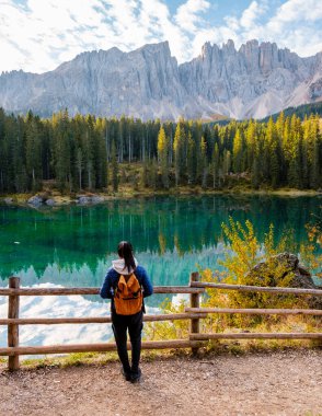 Bir gezgin, İtalya 'nın görkemli Dolomitleri' nde yükselen tepeler ve canlı sonbahar yapraklarıyla çevrili bir gölün el değmemiş zümrüt sularından büyülenir. Carezza Gölü veya Karersee 