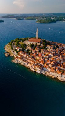 Hırvatistan 'ın Rovinj kıyı şeridinde canlı çatılar yuva kurarken, sıcak güneş ışığı kenti yıkıyor. Huzurlu deniz manzarayı sarar ve sakin bir atmosfer yaratır..